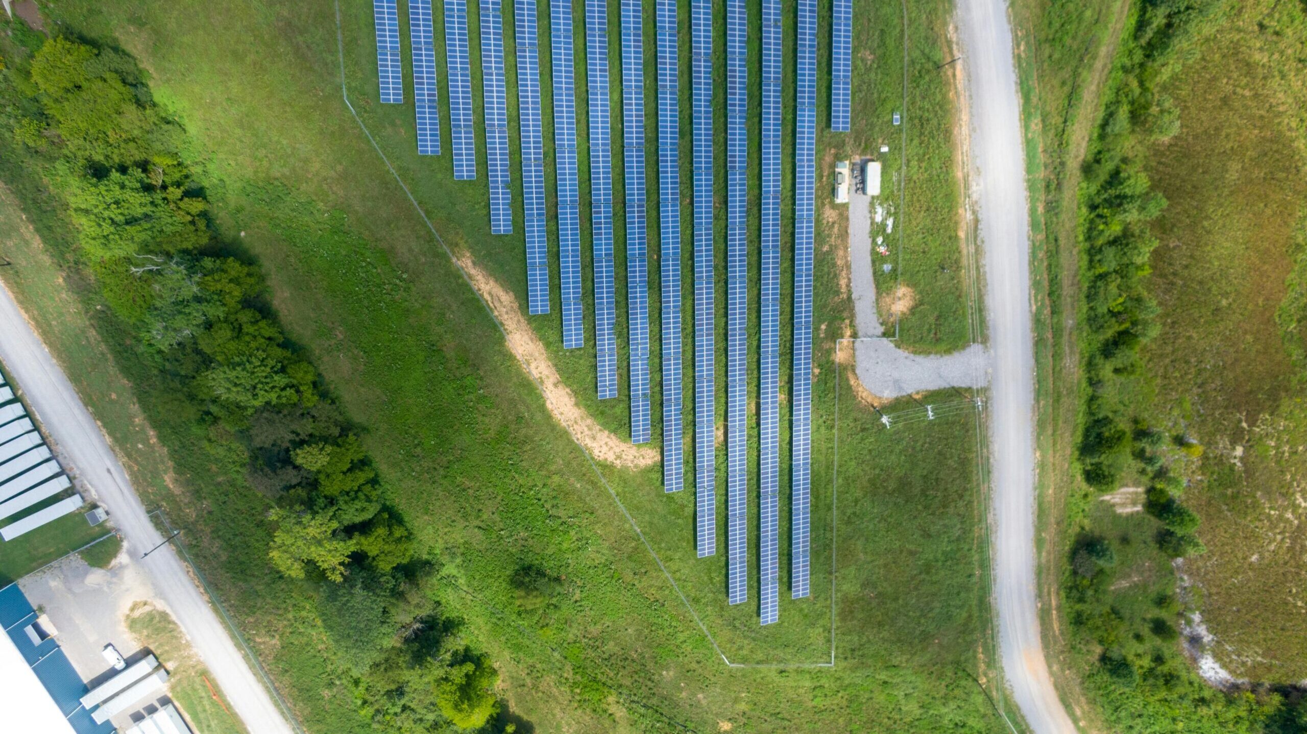 Aerial view showing a solar panel array in a lush rural landscape with a road.